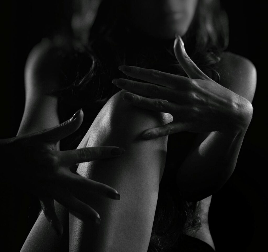 Dramatic black and white silhouette of a woman's hands and body in studio lighting.